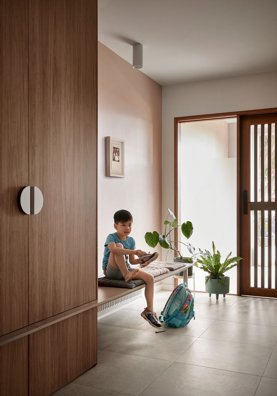 A young boy is sitting on a bench in a hallway.