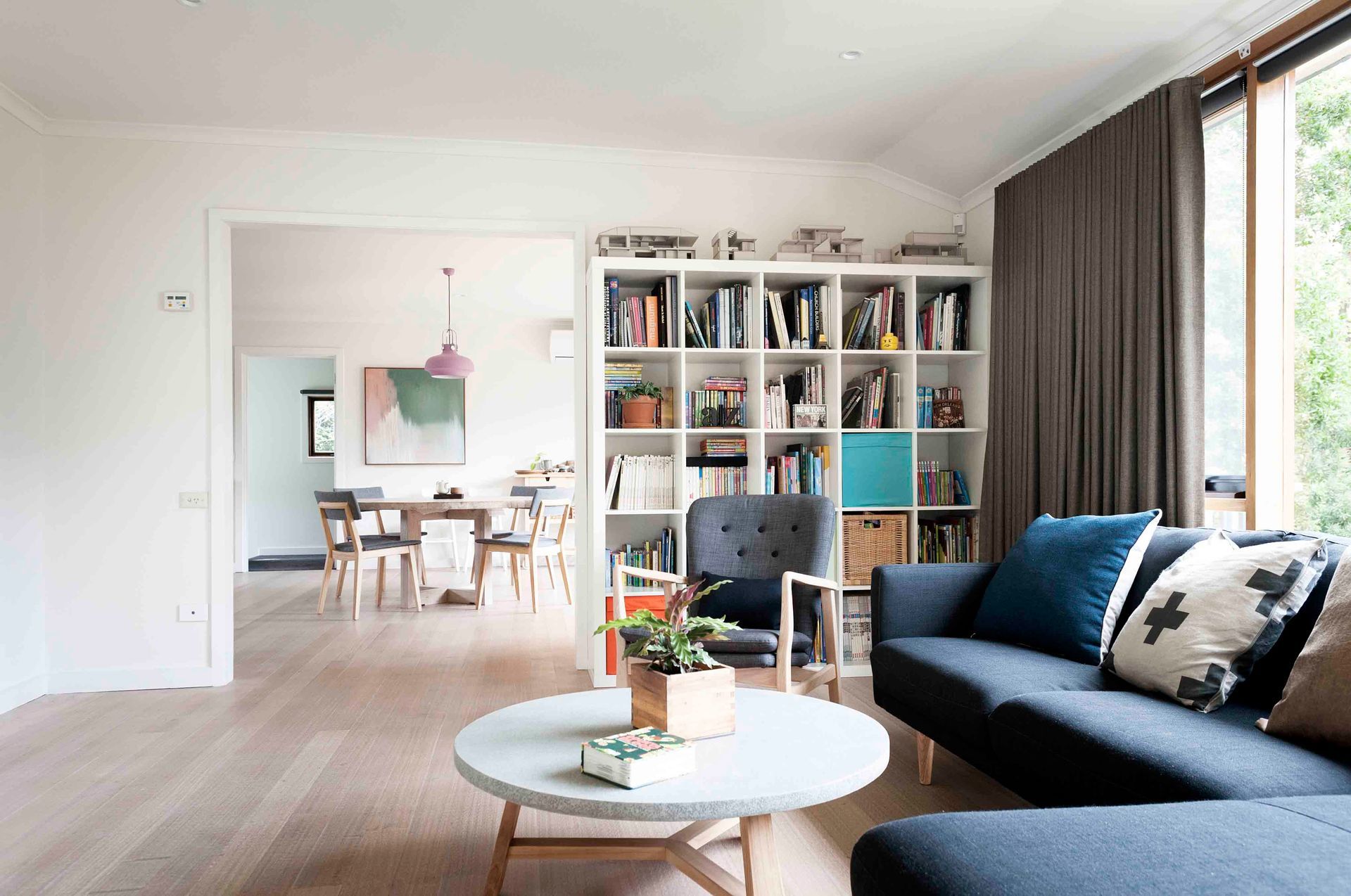 A living room with a couch , table , chairs and a bookshelf.