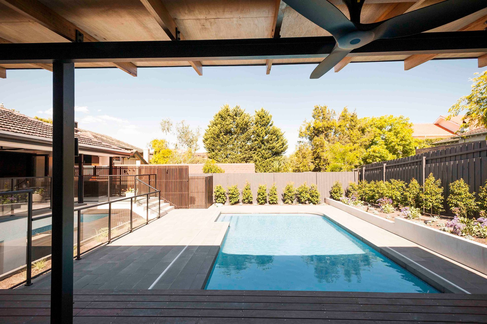 There is a large swimming pool in the backyard of a house.