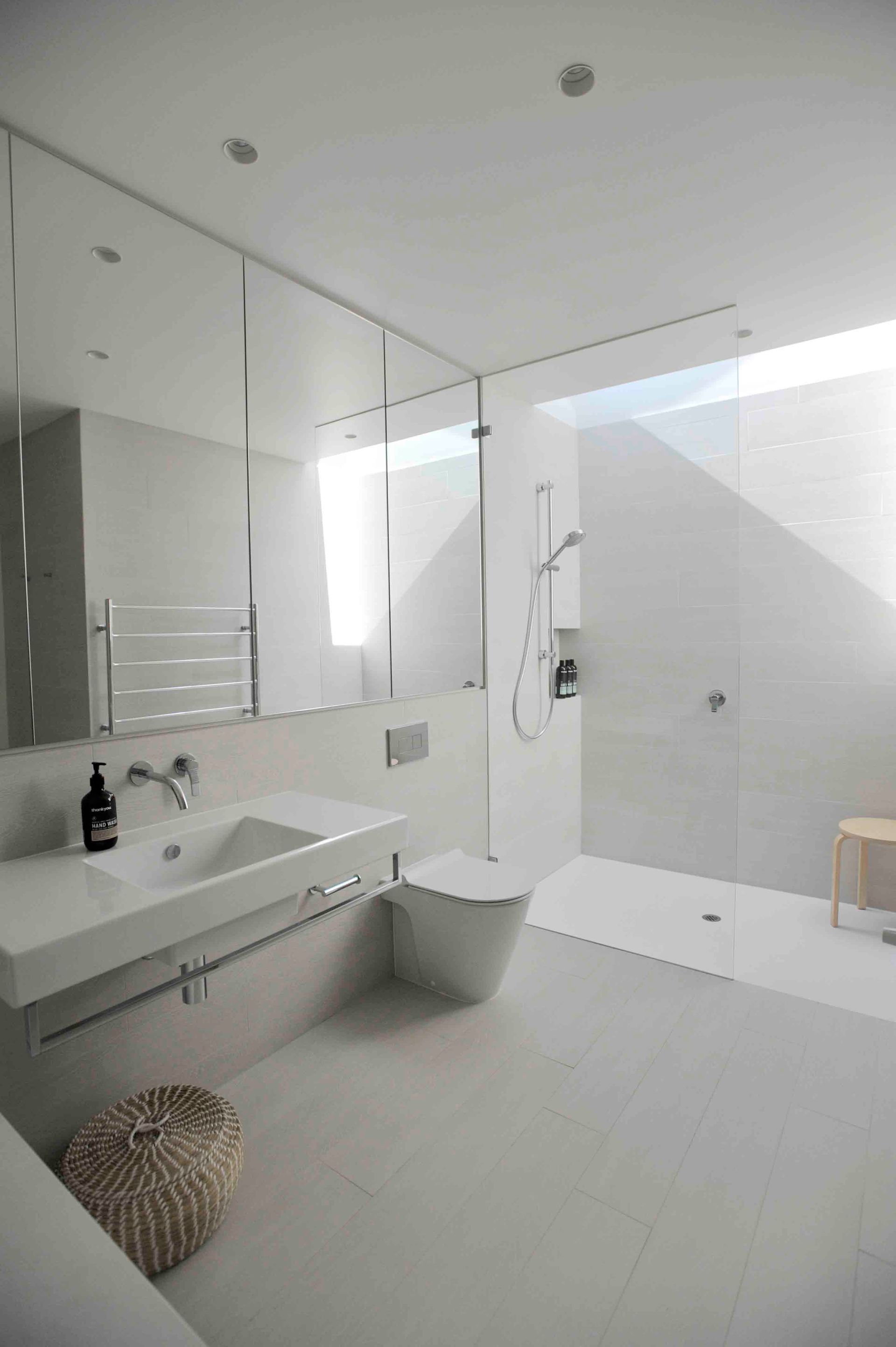 A bathroom with a sink , toilet , shower and mirror.