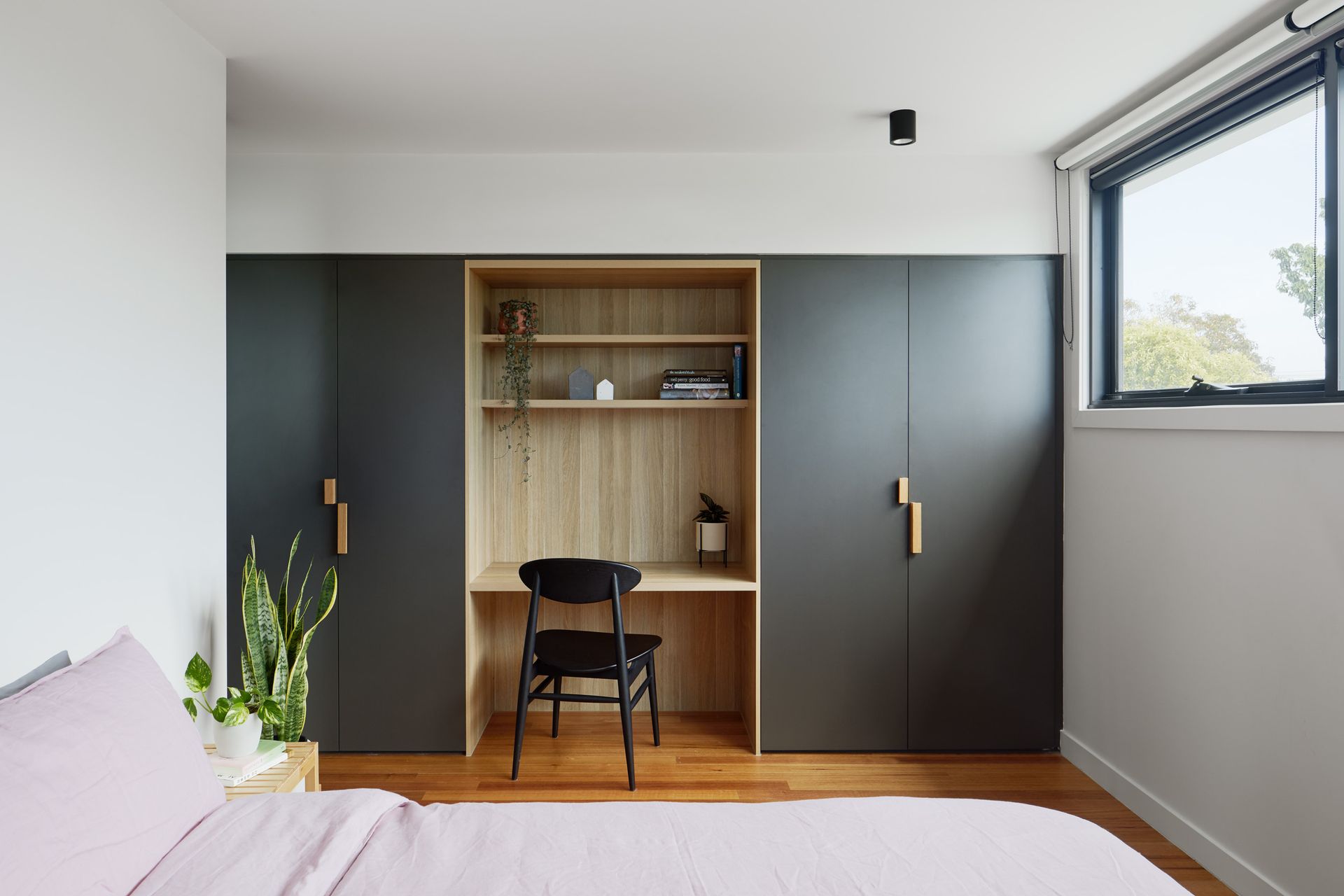 A bedroom with a bed , chair , desk and wardrobes.