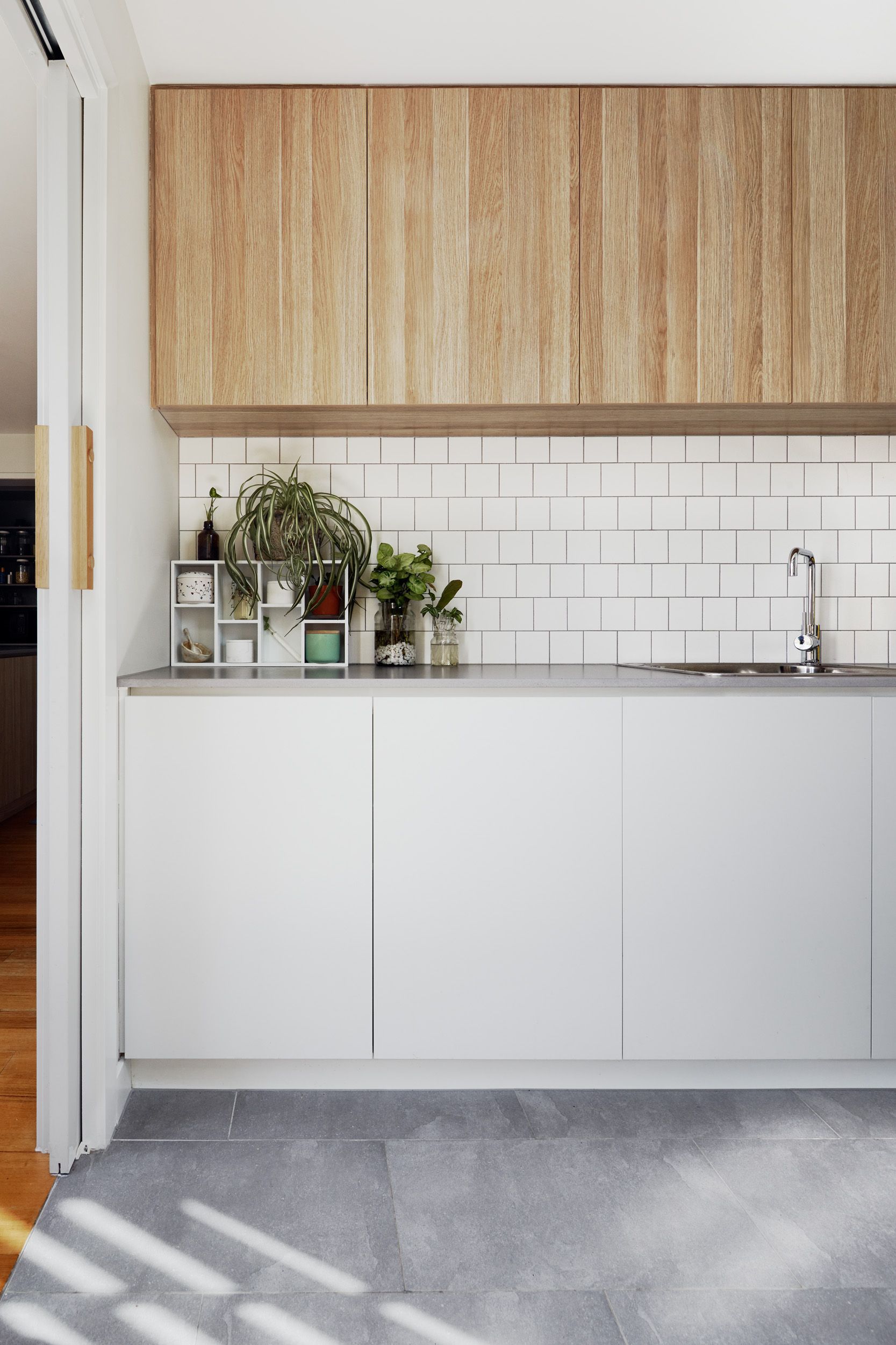 A kitchen with white cabinets and wooden cabinets and a sink.