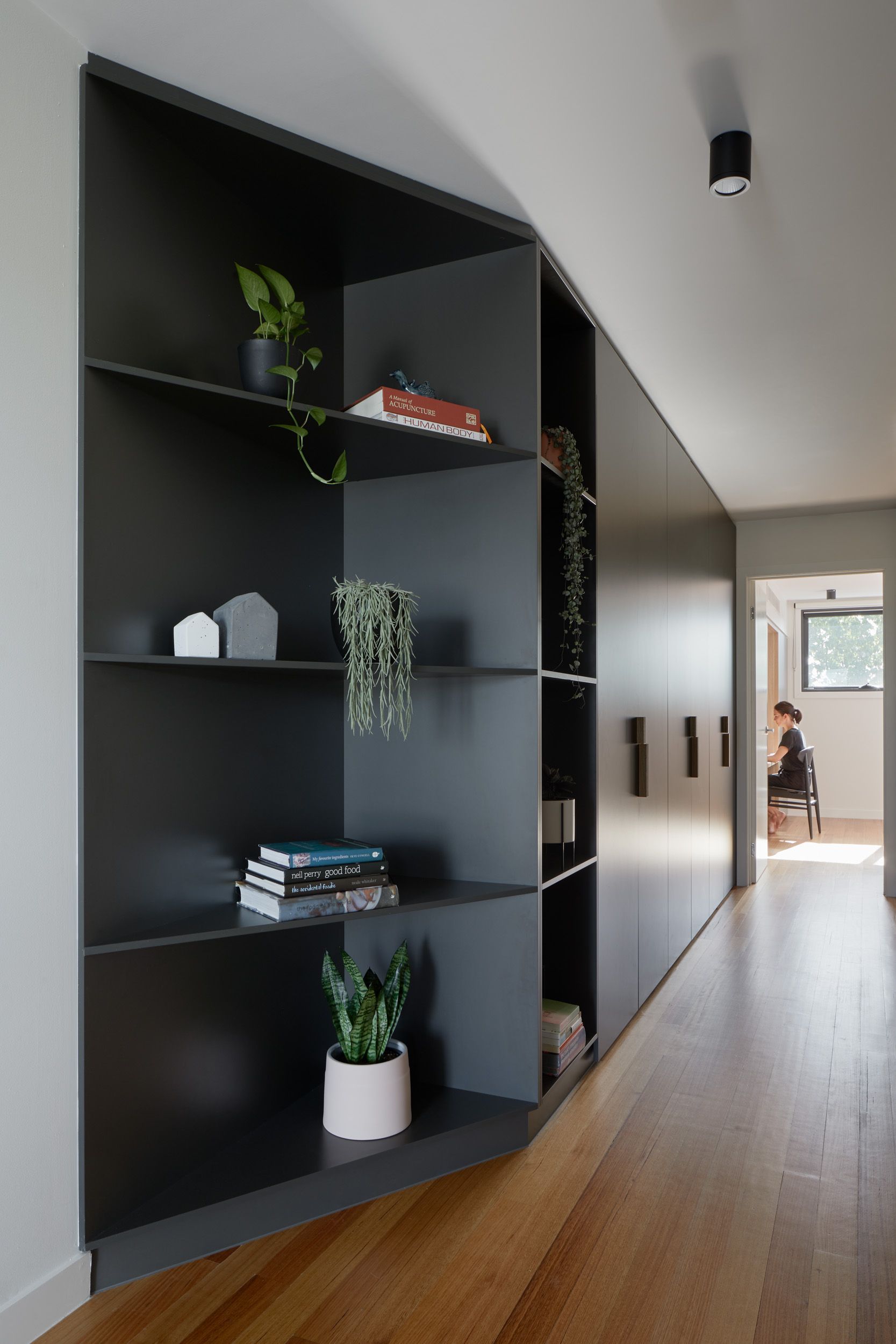 A long hallway with black shelves and wooden floors.