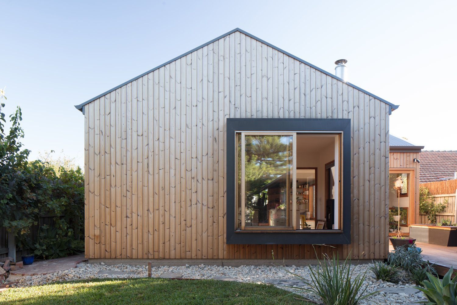 A wooden house with a large window in the backyard.