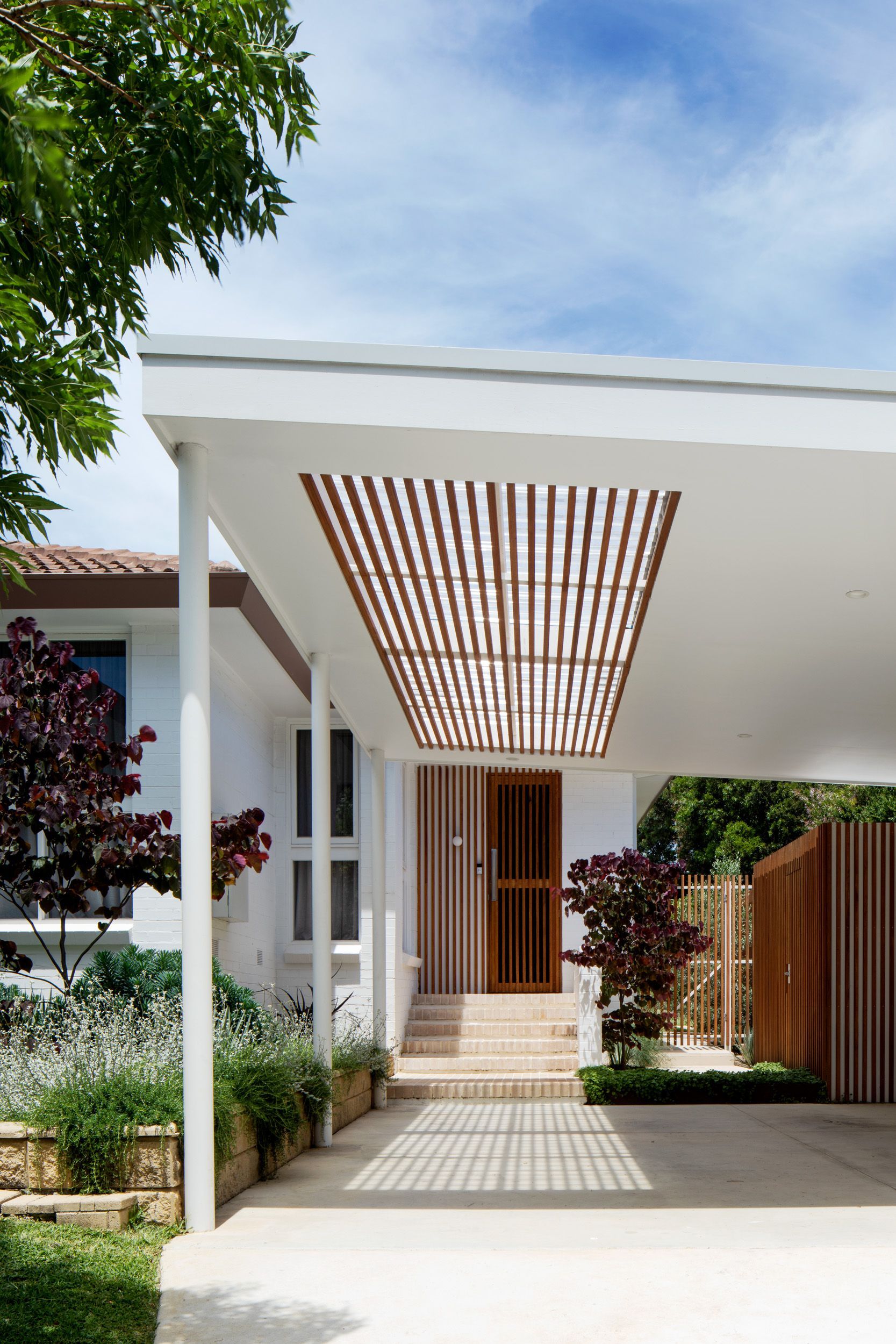 A white house with a carport and a wooden door.