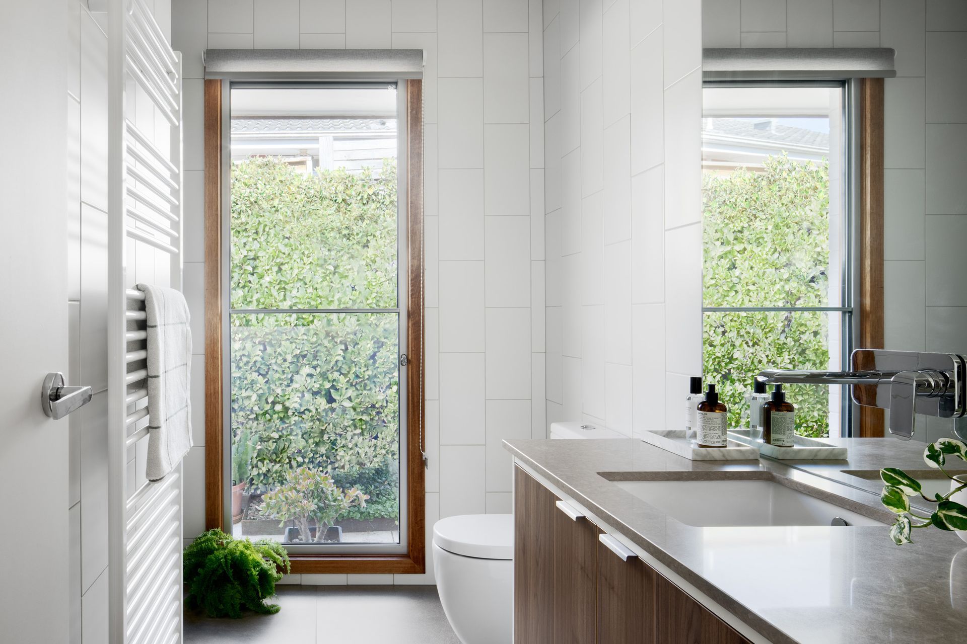 A bathroom with a sink , toilet , mirror and window.