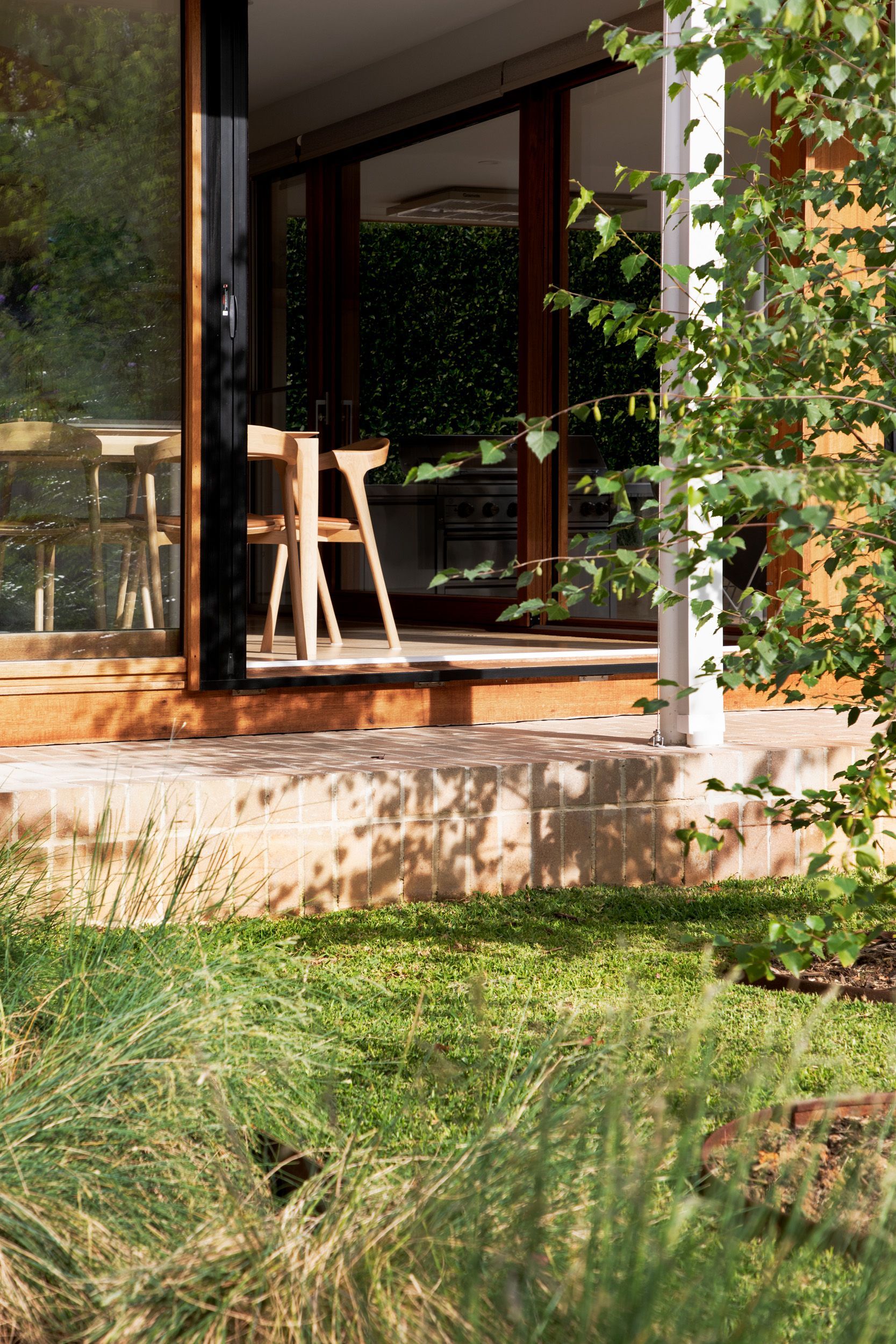 A patio with a sliding glass door and chairs in front of a house.