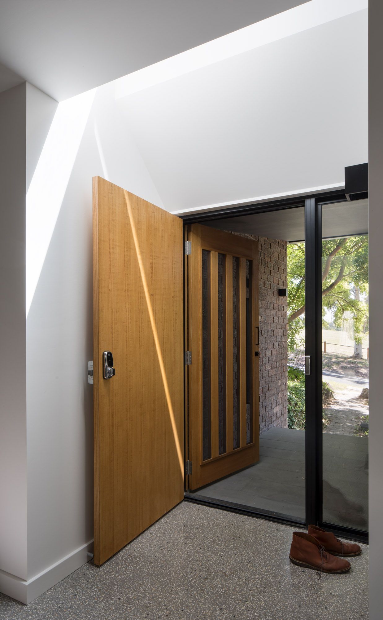 A wooden door with a sliding glass door is open in a hallway.