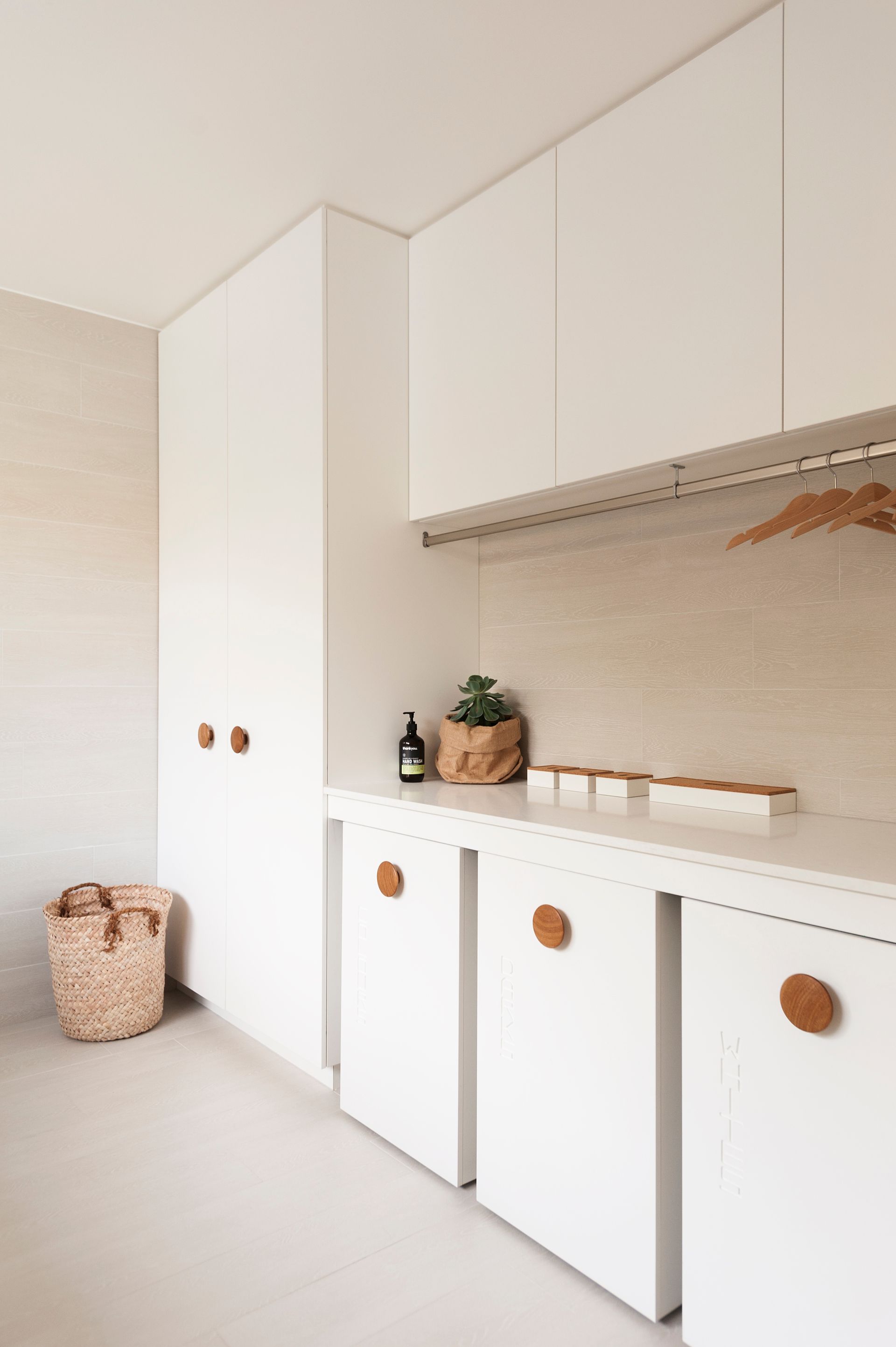 A laundry room with white cabinets and wooden handles.