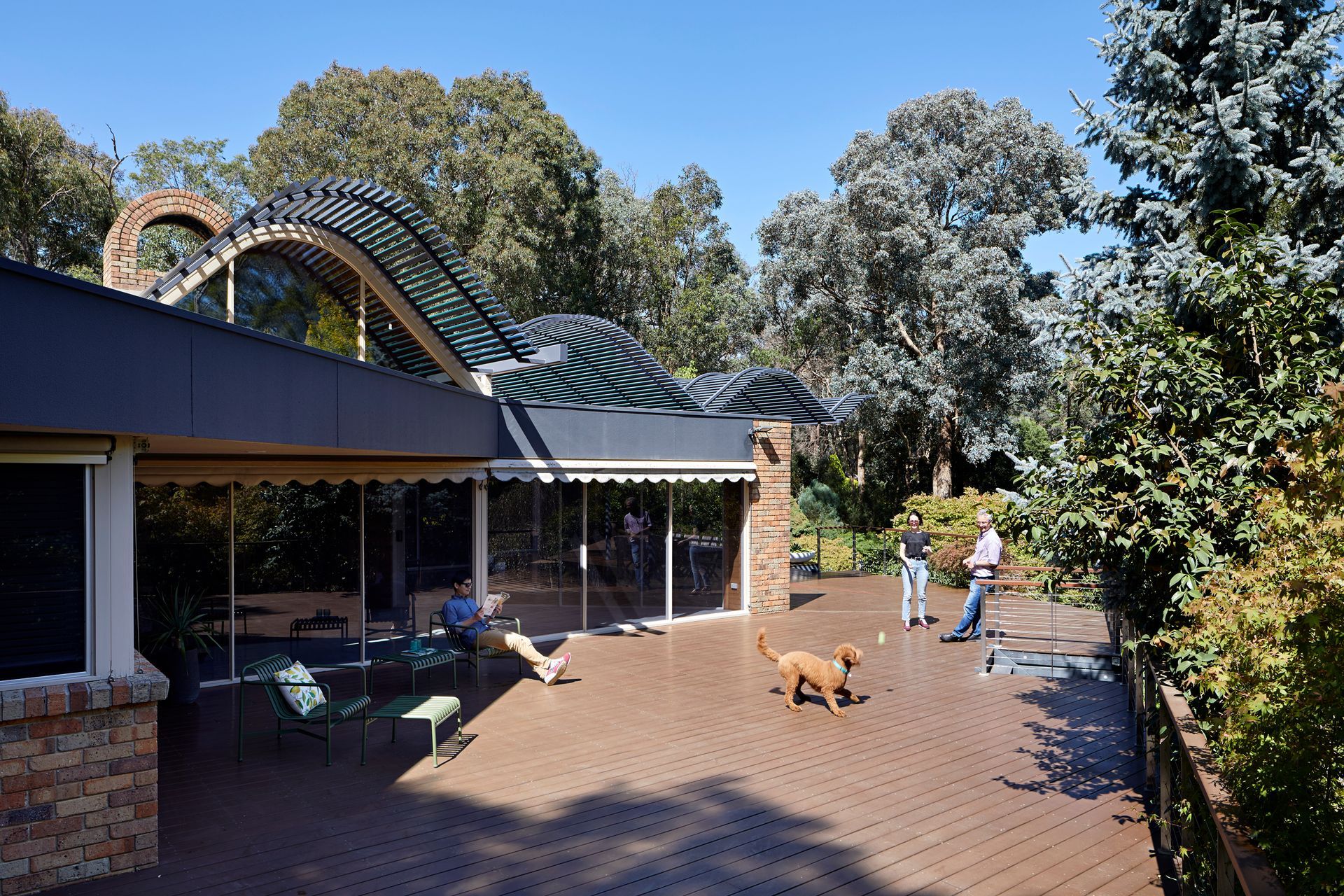A dog is walking on a deck in front of a house