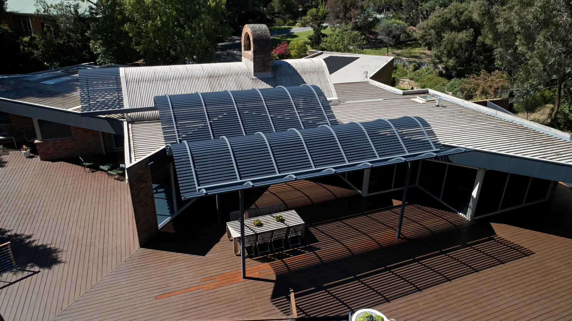 An aerial view of a house with a covered patio and trees in the background.