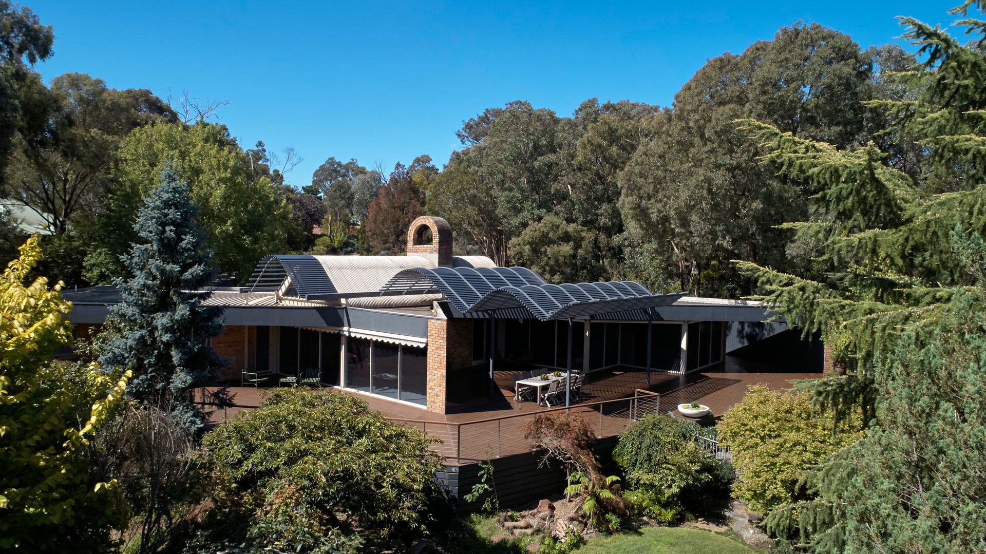 A large house is surrounded by trees on a sunny day