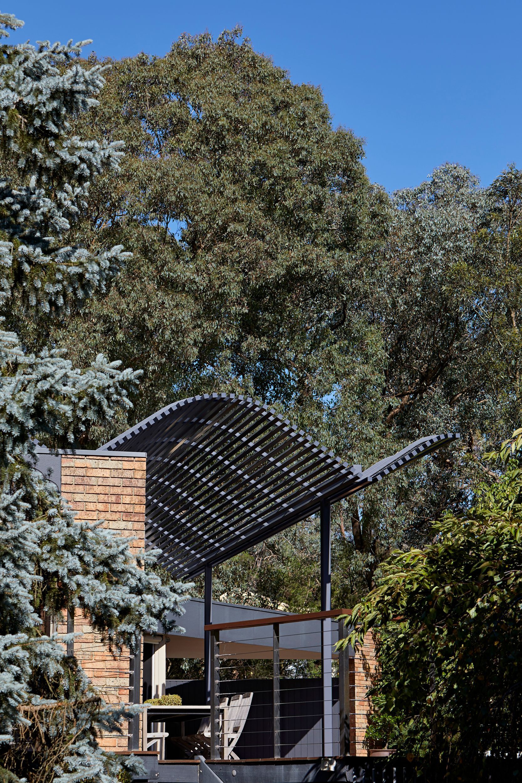 A house with a roof that is surrounded by trees on a sunny day.