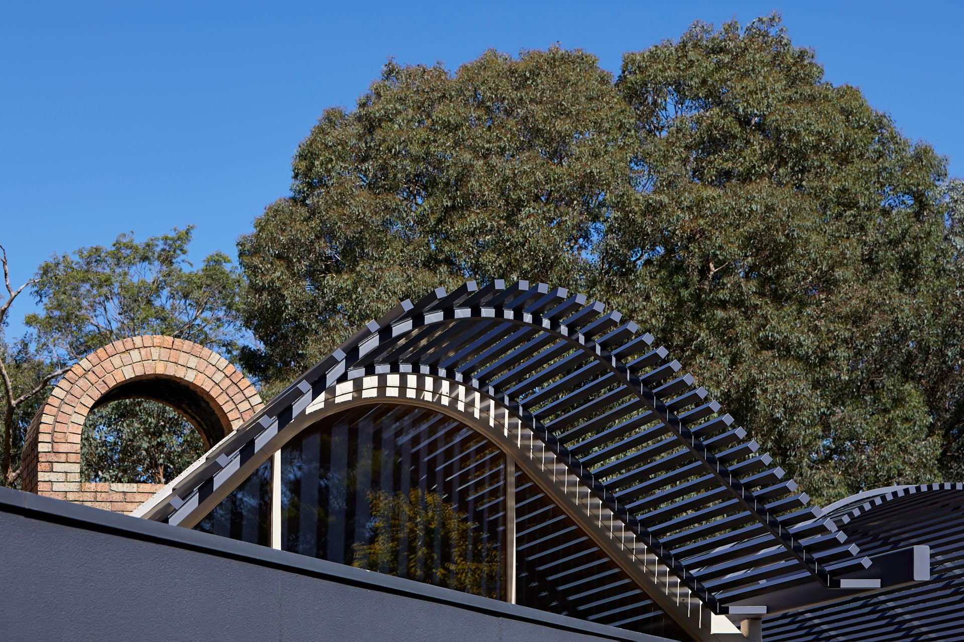 A building with a curved roof and a tree in the background.