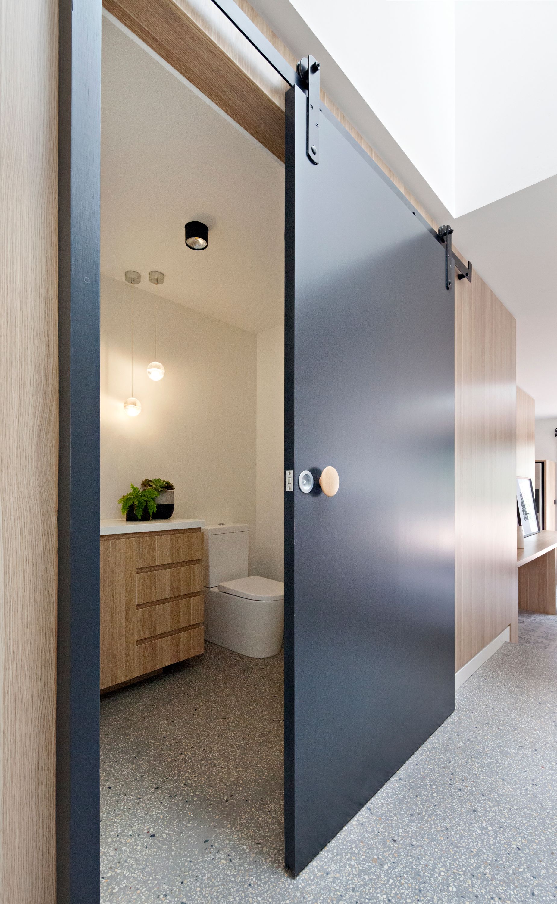 A bathroom with a sliding barn door leading to it.