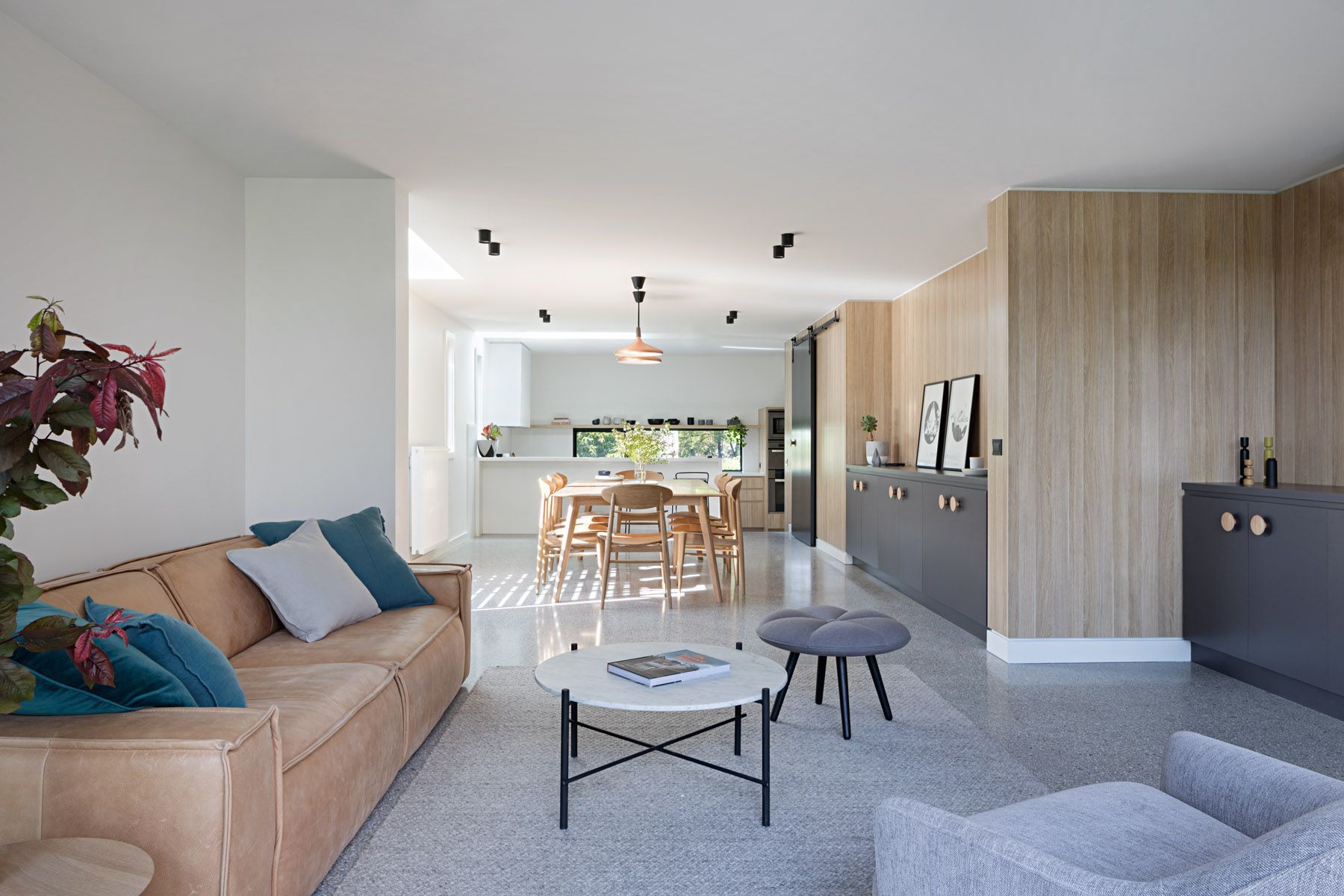 A living room with a couch , chair , coffee table and dining table.