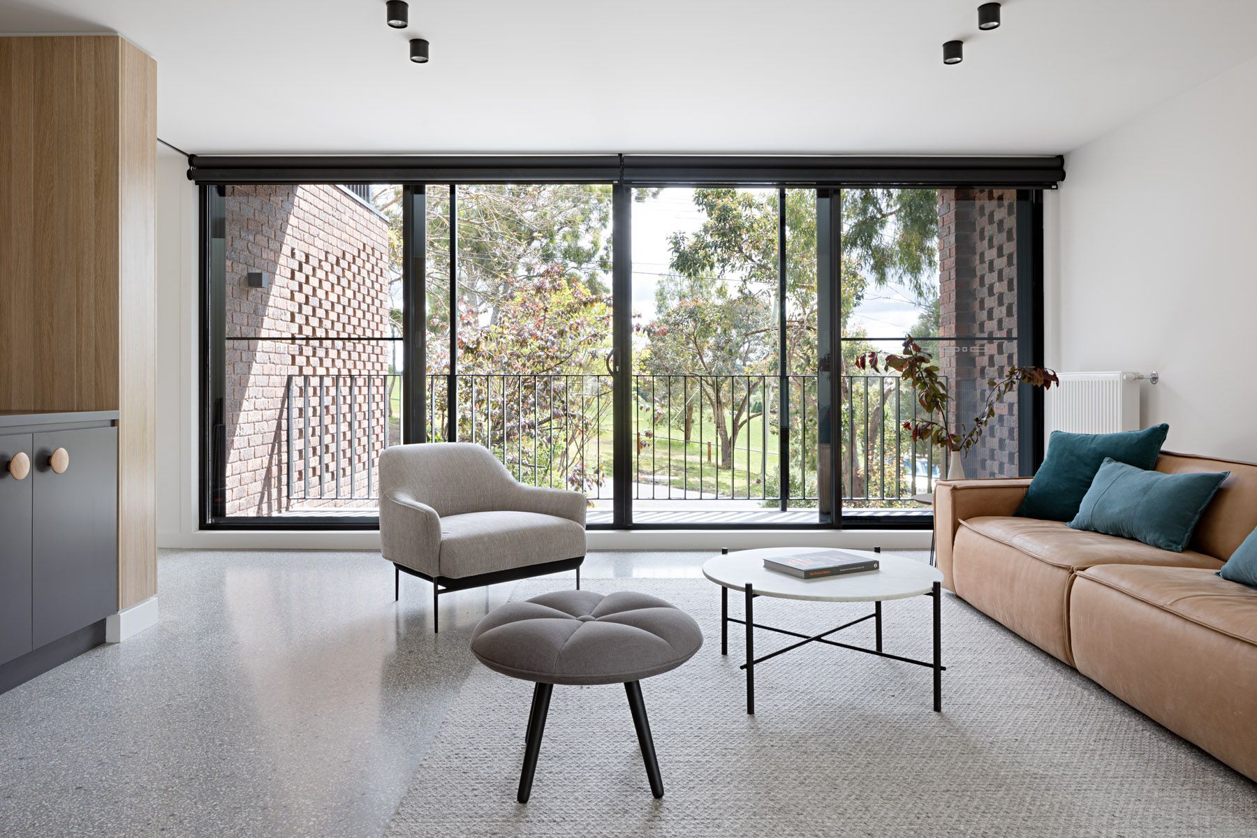 A living room with a couch , chair , coffee table and balcony.