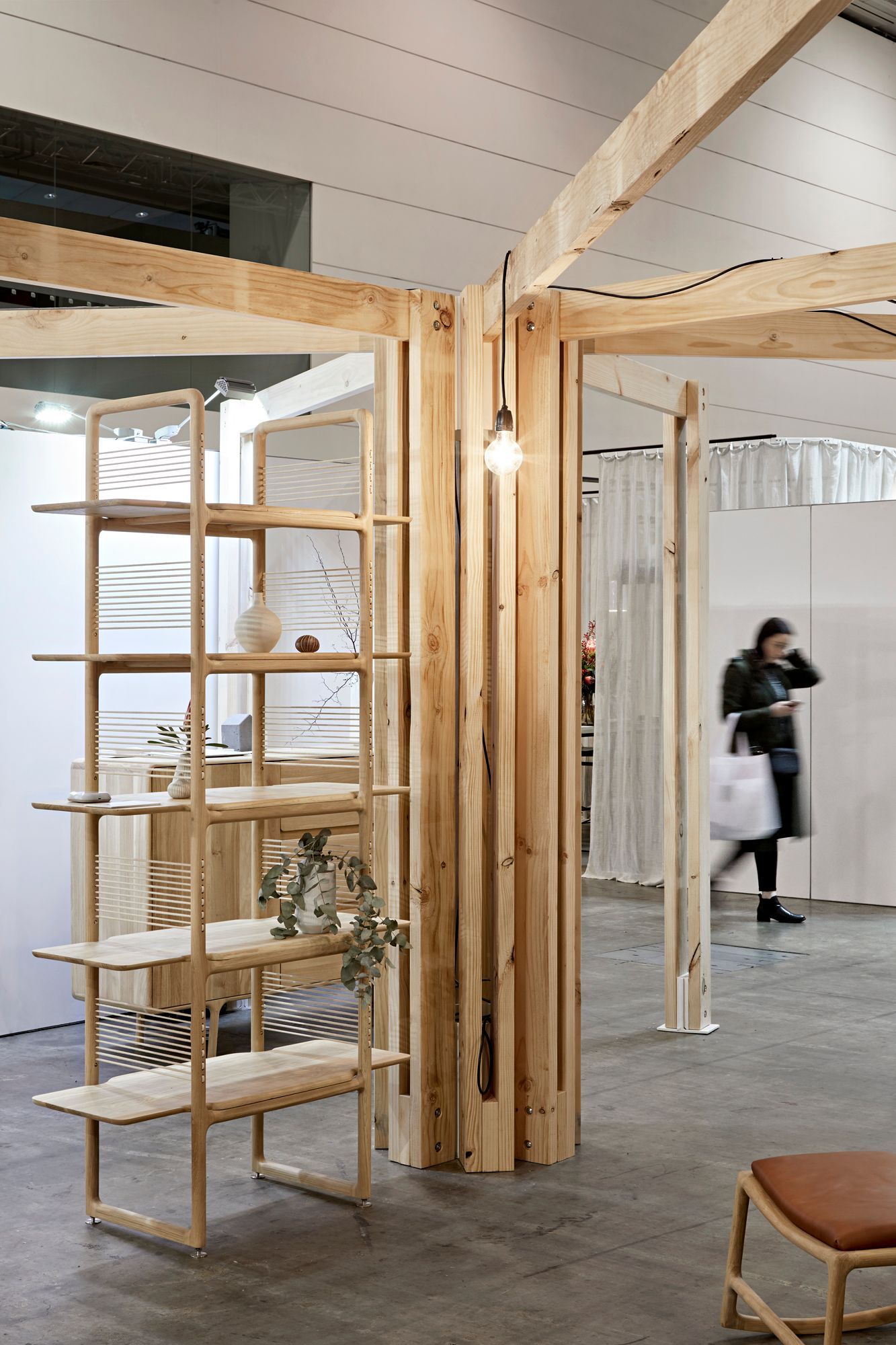 A woman is walking through a room with wooden shelves.