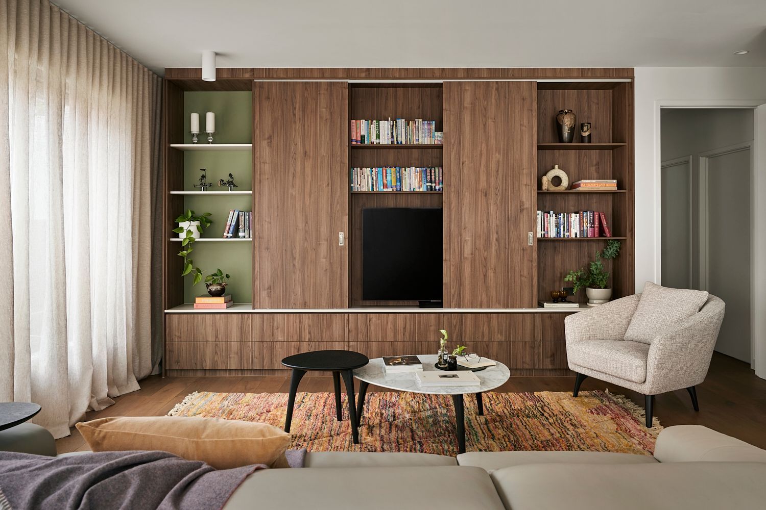 A living room with a couch , chair , coffee table and television.