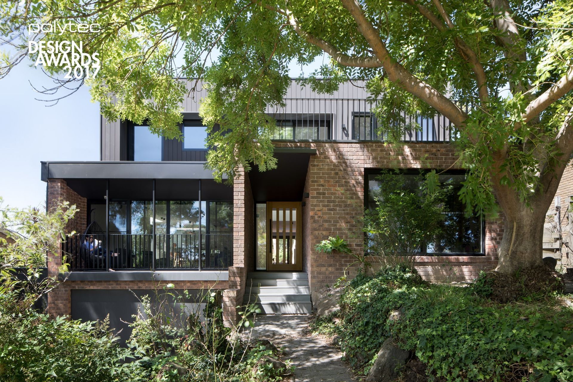 A large brick house with a tree in front of it.