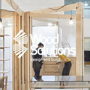 Two people are working on a wooden structure in a room.