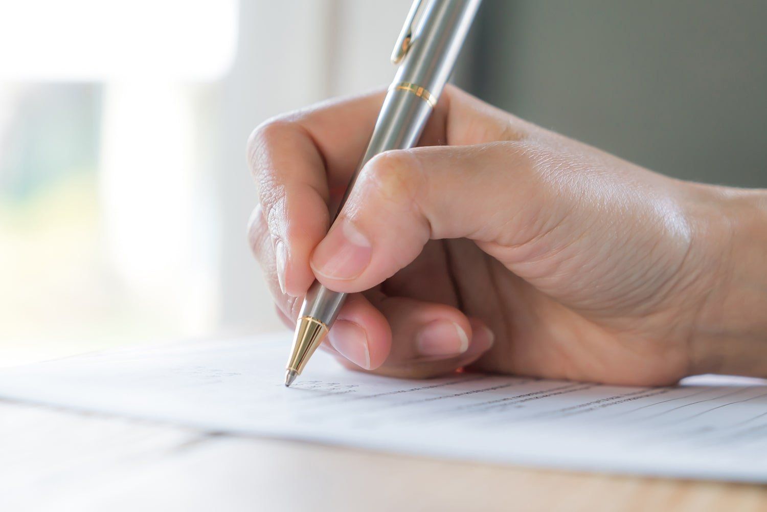 a person is writing on a piece of paper with a pen .