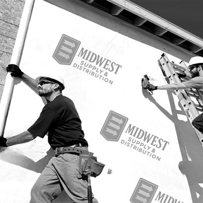 Two construction workers installing siding on a building, one on a ladder, in daylight.