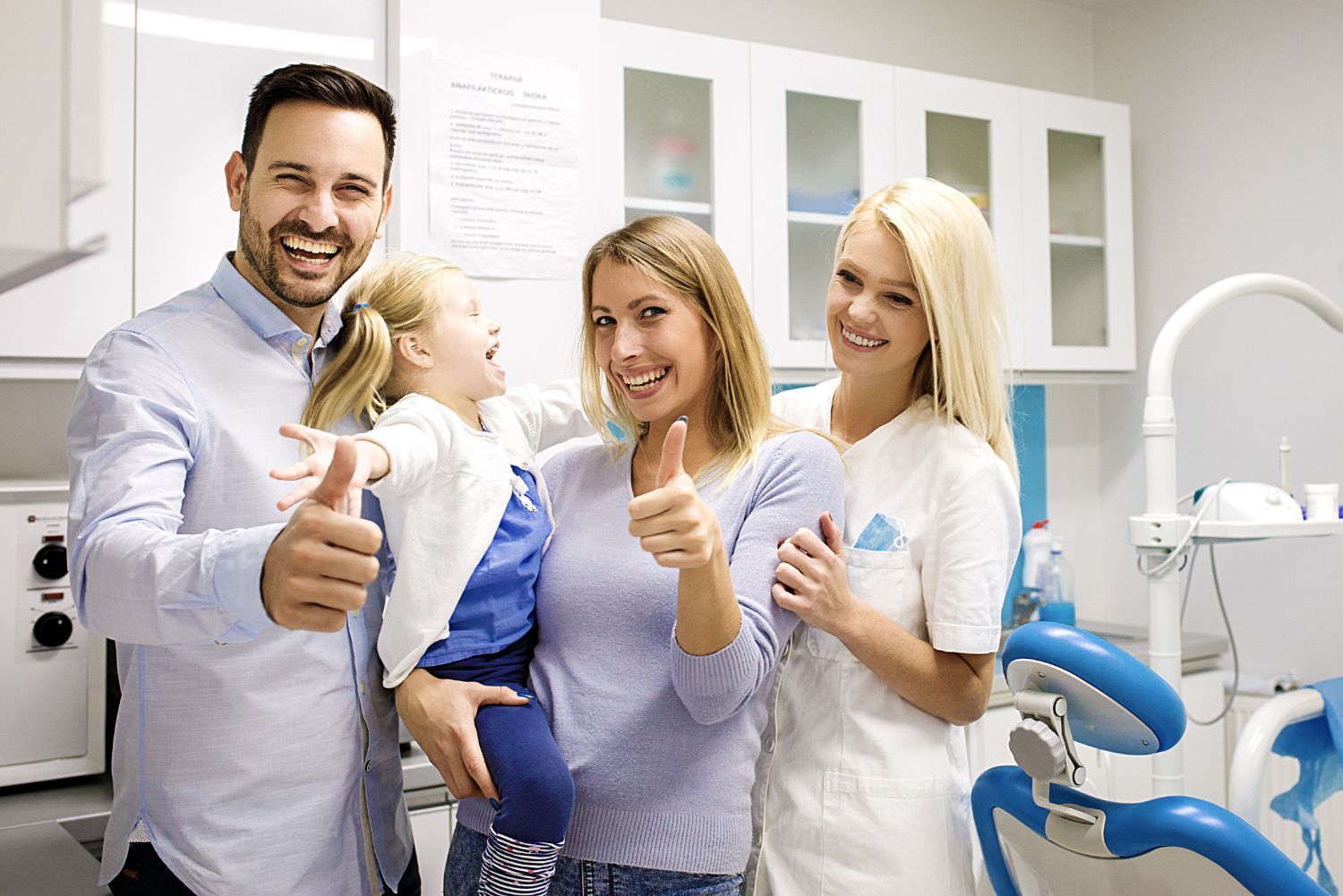A family is giving a thumbs up in a dental office.
