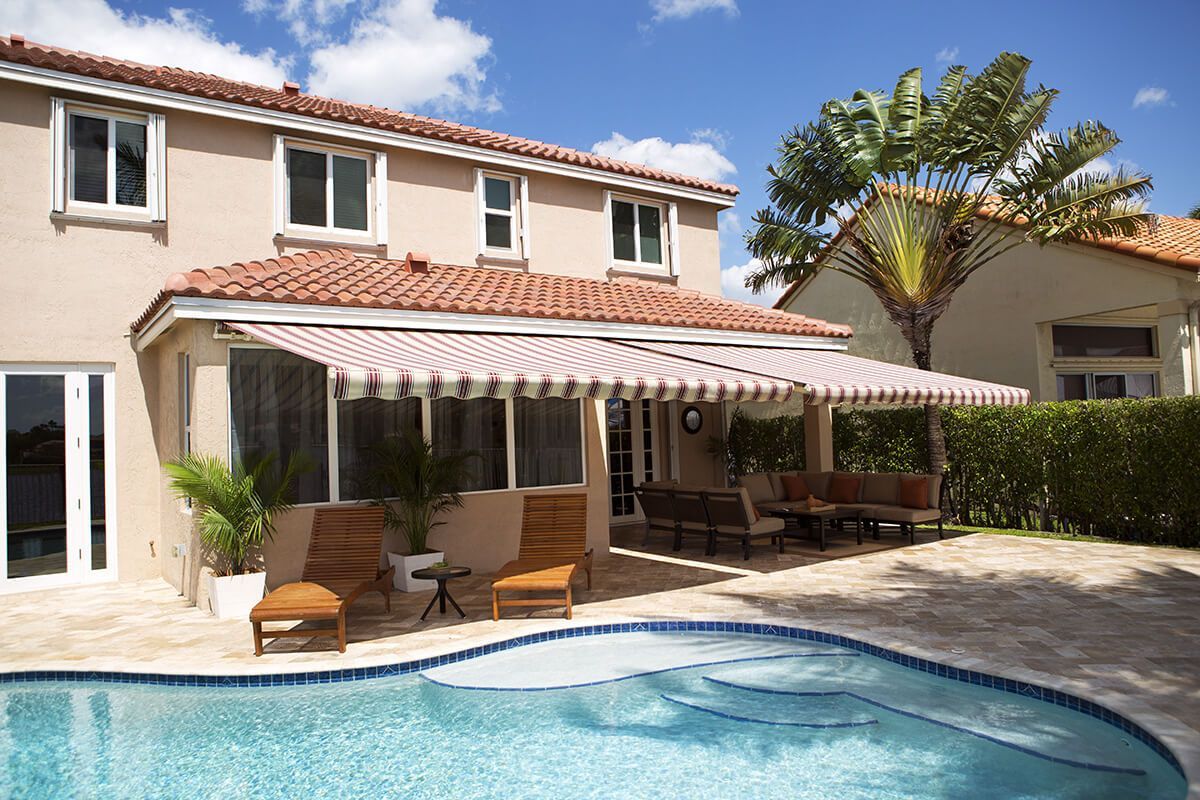 Backyard with pool, patio, awning, and two-story house.