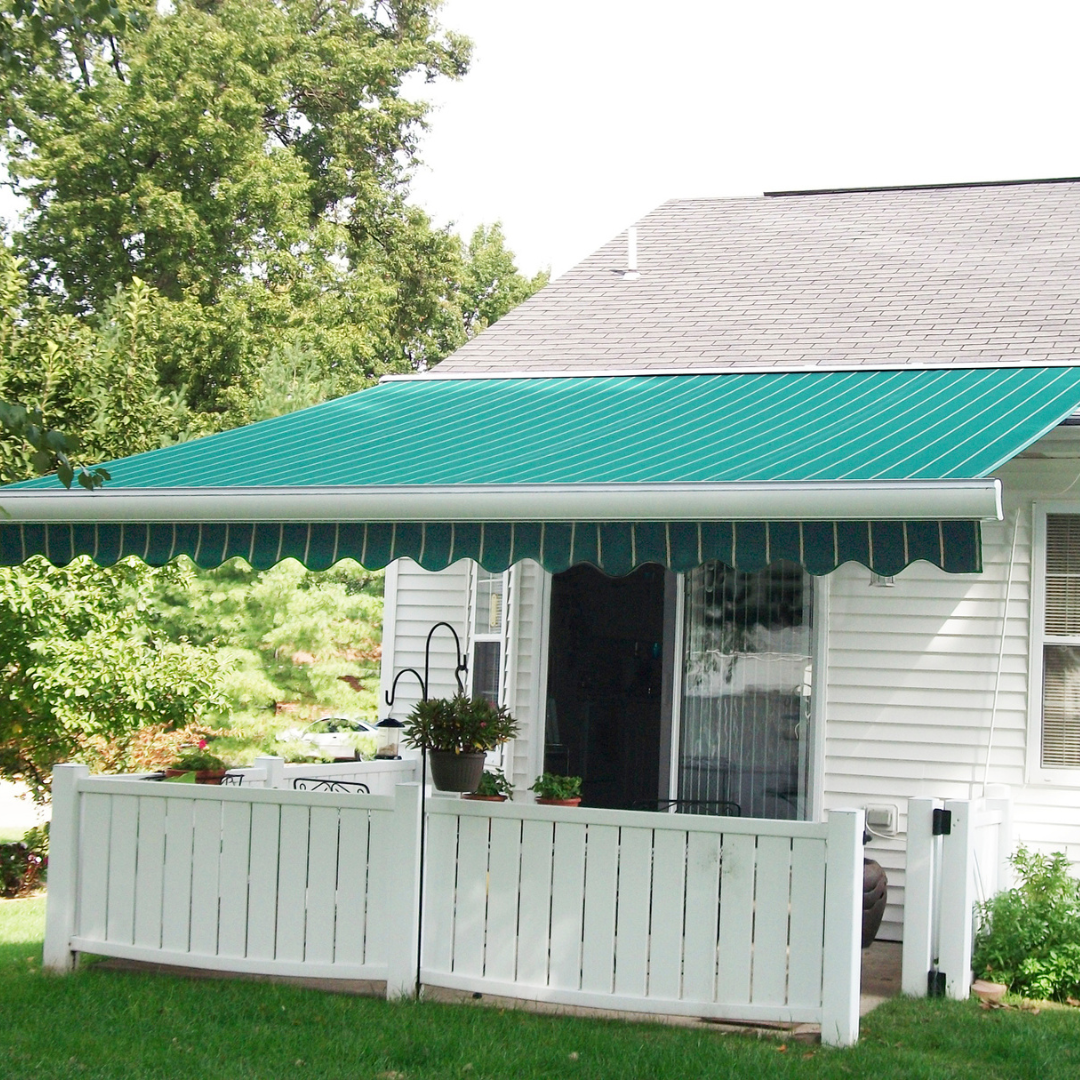 Green awning over a white-fenced patio outside a white house.