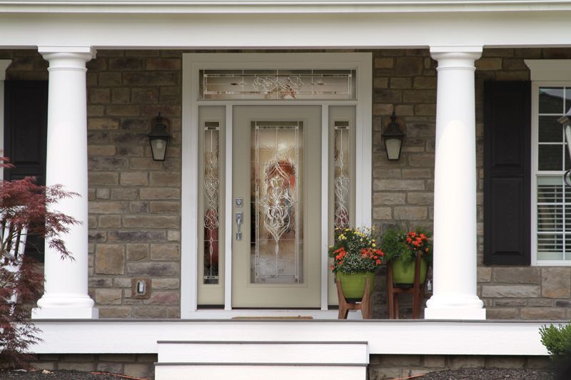 A light-colored front door with sidelights and transom is flanked by white columns.
