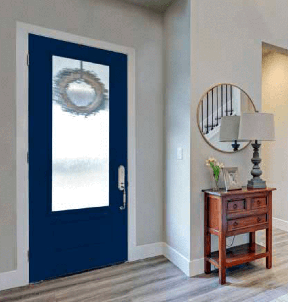 A navy blue front door with a large window, wreath, and smart lock; an entryway with a table, mirror, and lamp.