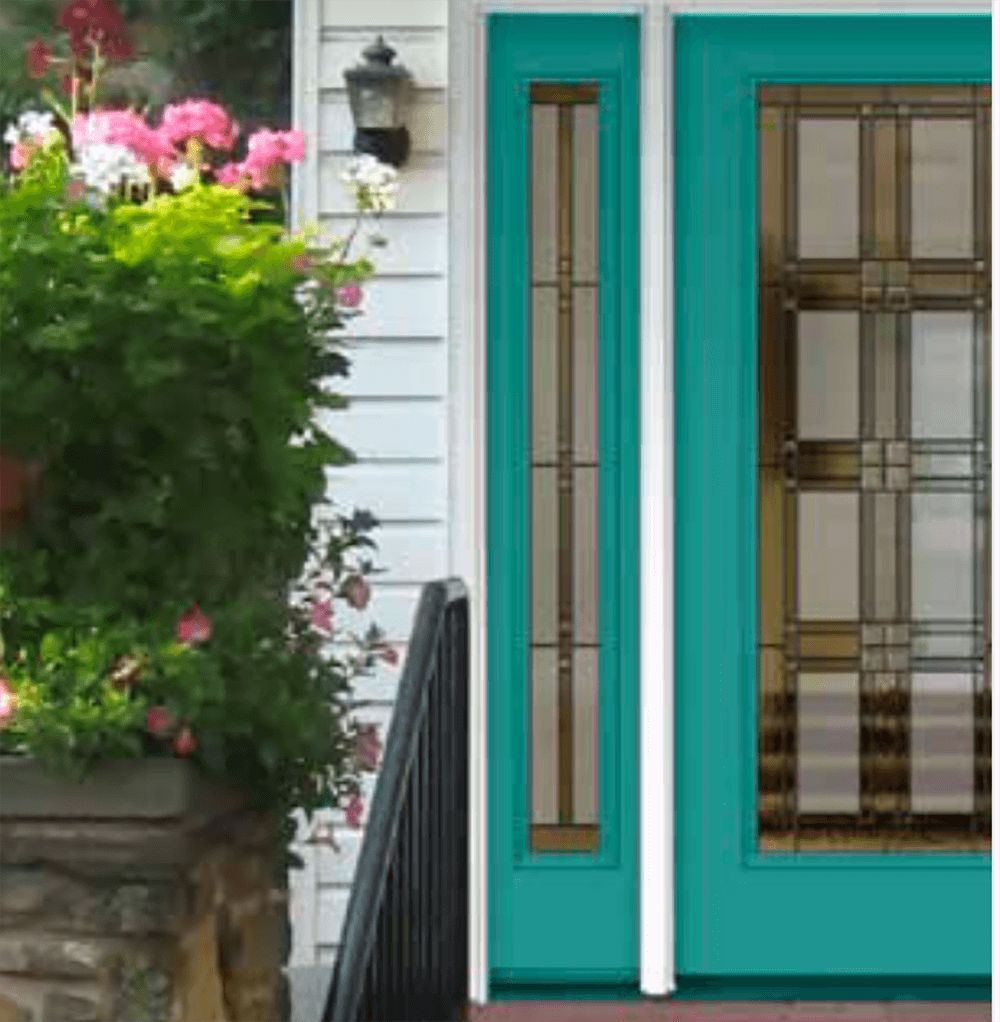 Teal front door with glass panels, next to a sidelight, and a stone and flower basket.