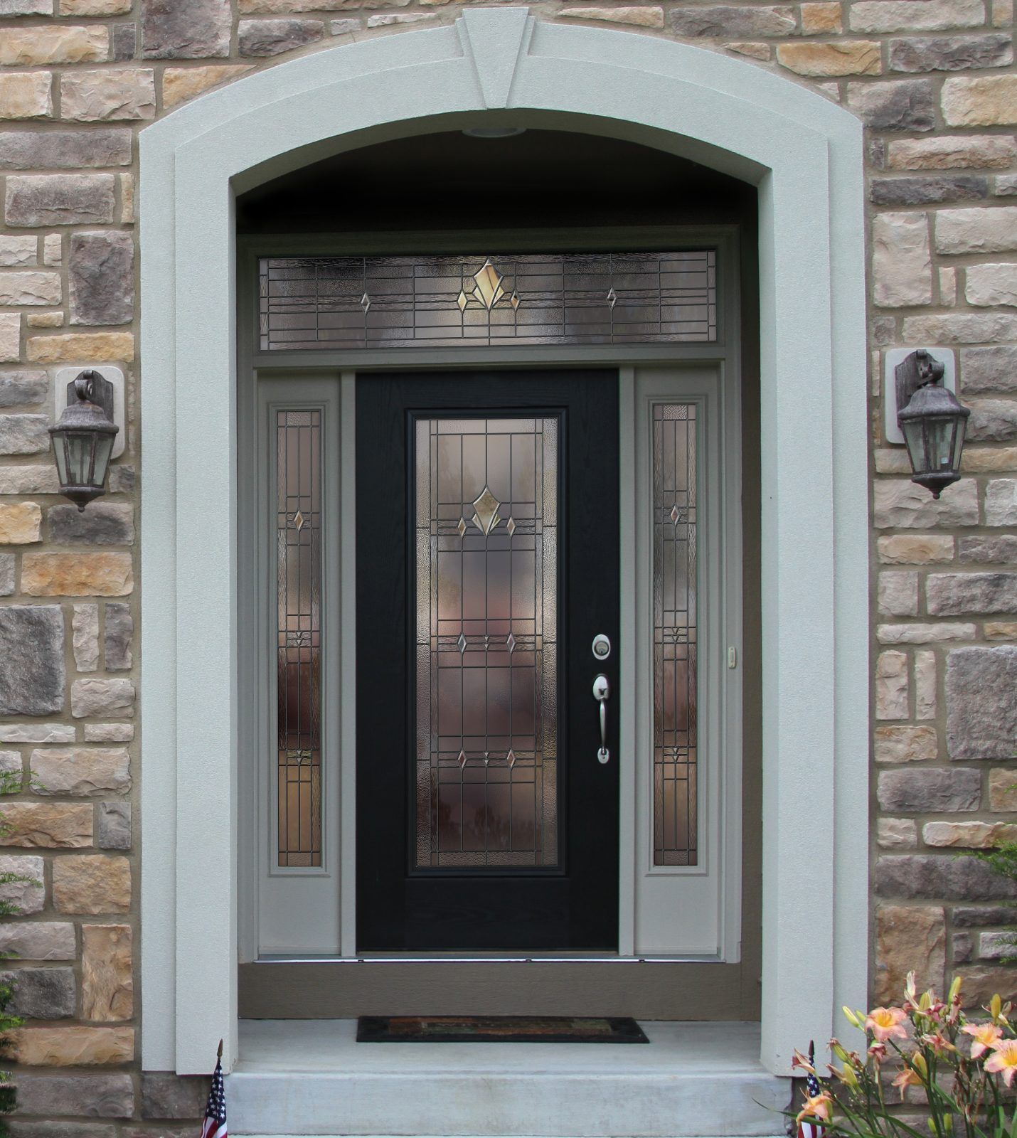 Black front door with glass panels, flanked by sidelights, set in a stone wall. 