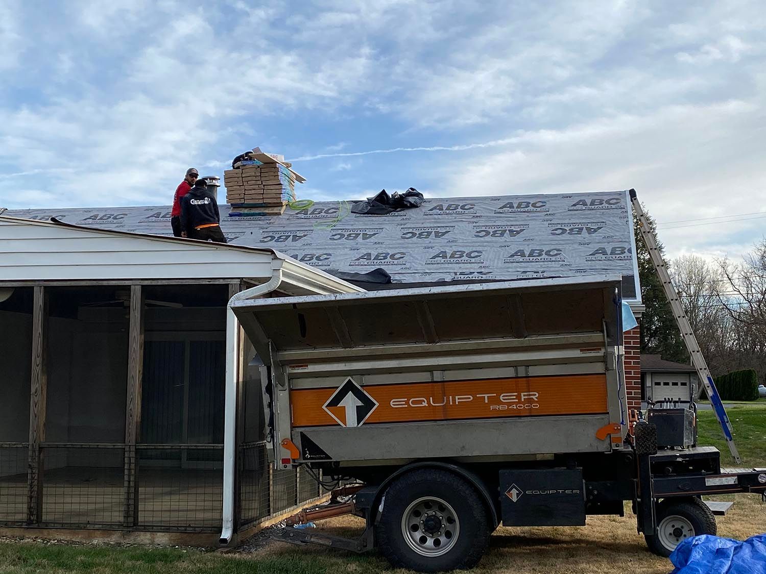 White building with a cupola, dormers, stone accents, and black shutters. Sunny day with clear blue sky.