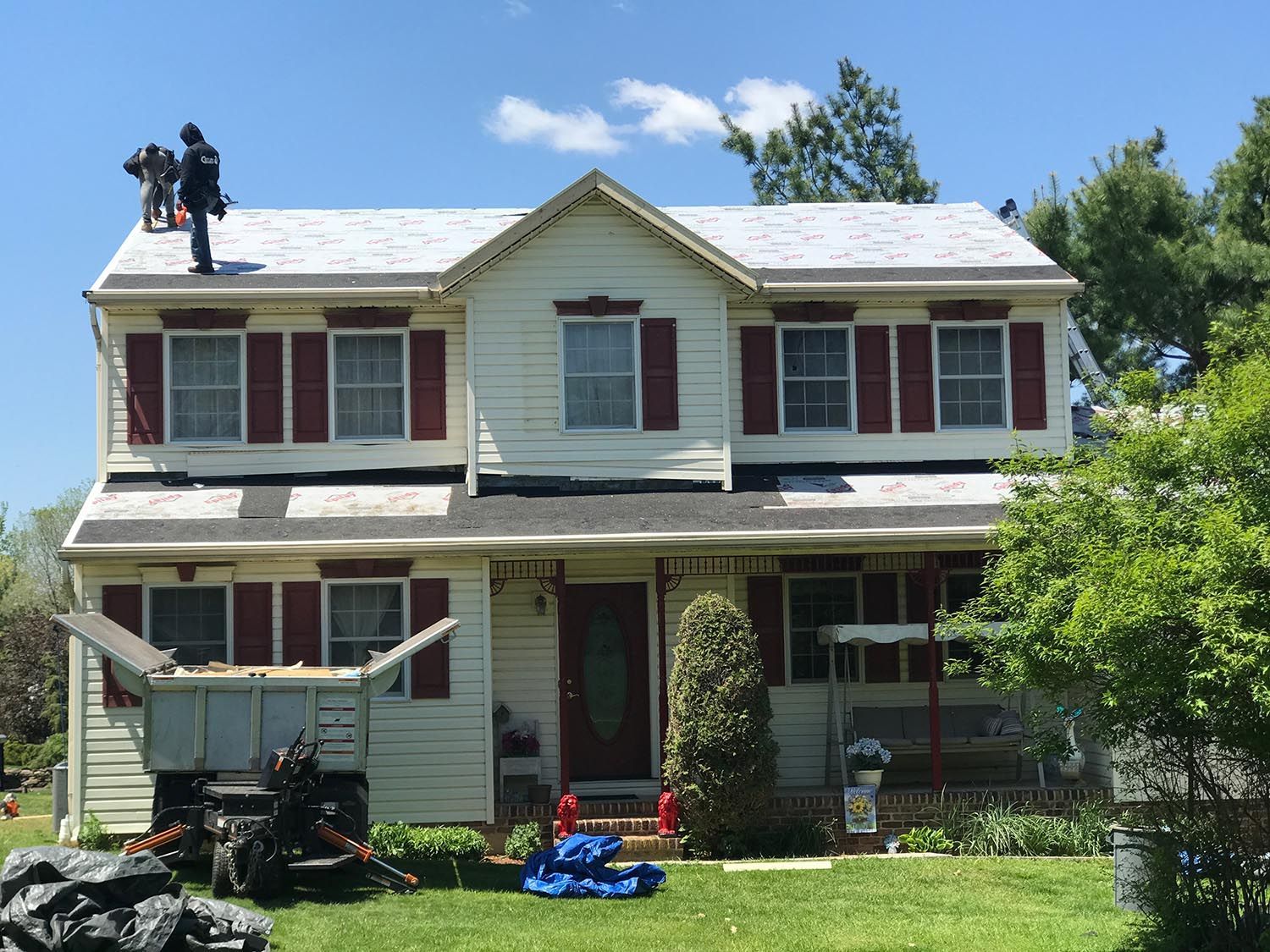 White house with a cupola on top, featuring stone pillars and white gutters under a blue sky.