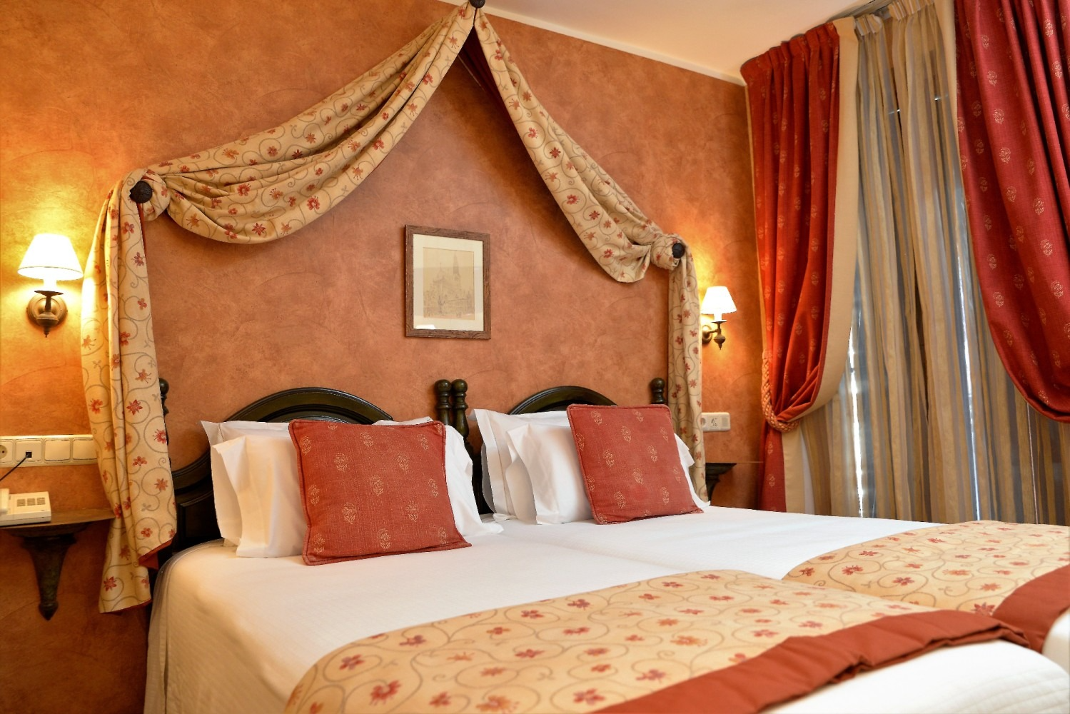 Habitación de hotel con dosel y detalles en rojo y dorado.