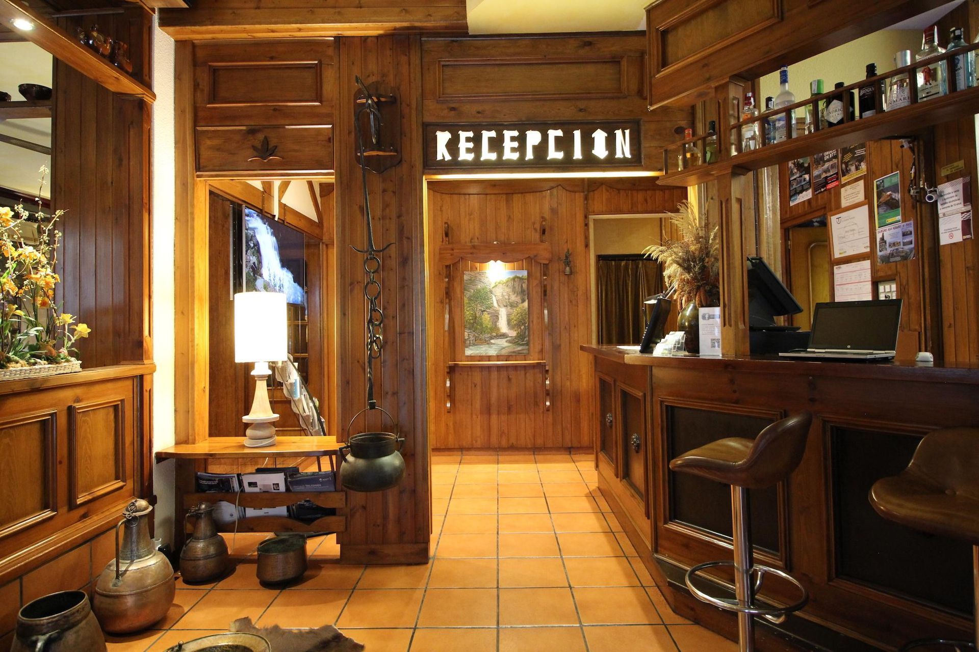 Recepción y vestíbulo de madera. Iluminación cálida, suelo de piedra, letrero de 