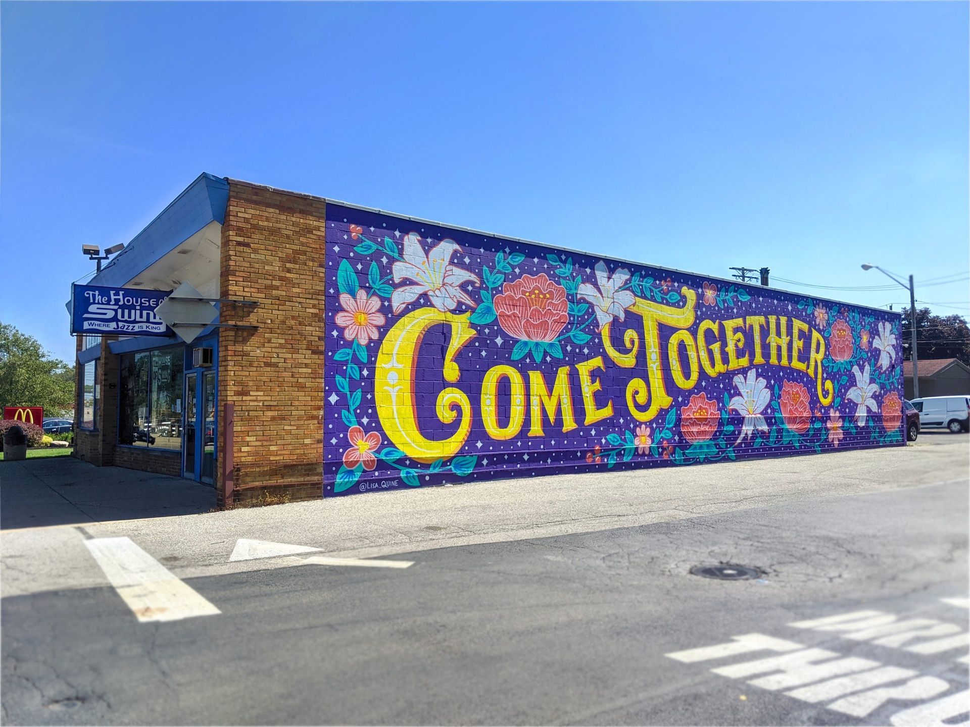 A large mural on the side of a building that says `` come together ''.