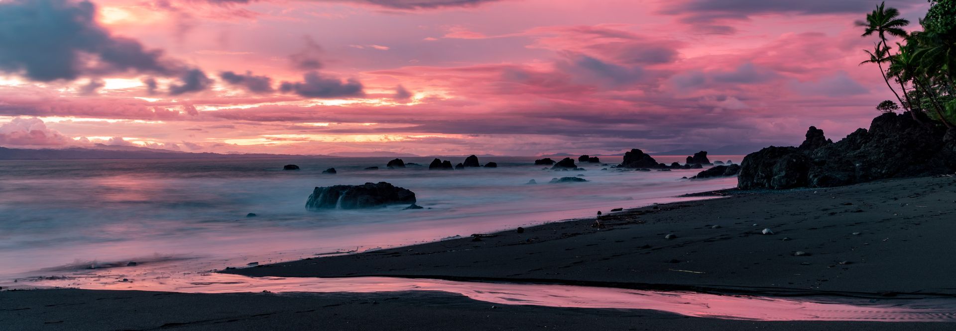 A sunset over a beach with a lot of rocks in the water.