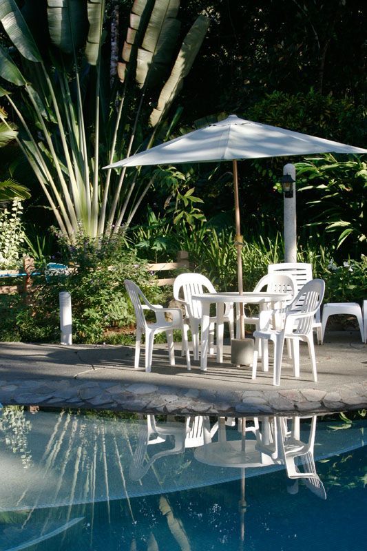 A table and chairs under an umbrella next to a swimming pool