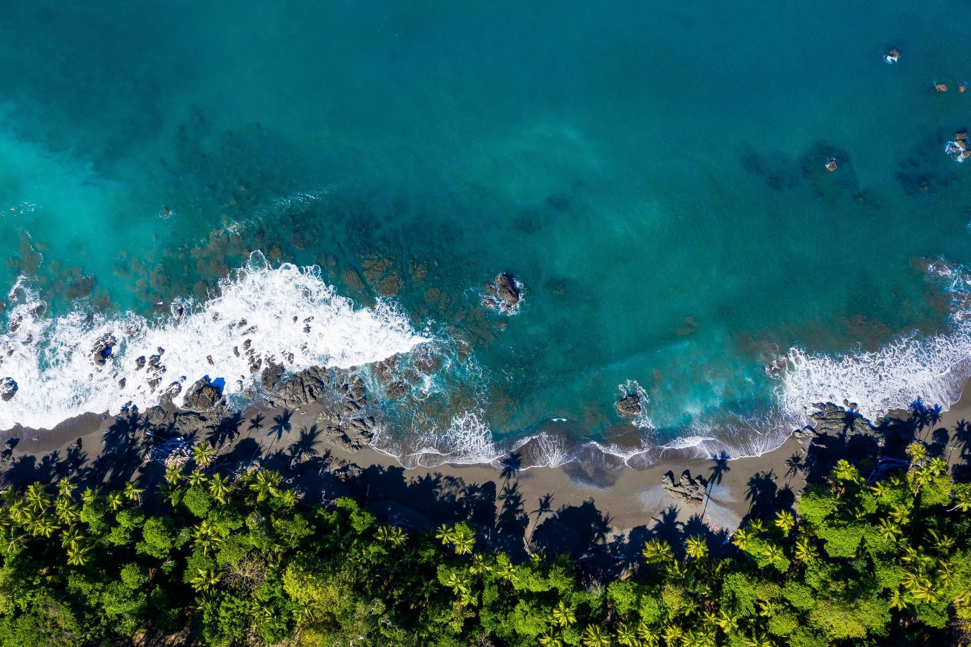An aerial view of a beach with waves crashing on the shore.