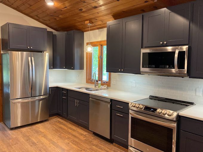 A kitchen with stainless steel appliances and gray cabinets.