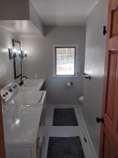 A bathroom with a washer and dryer and a window.