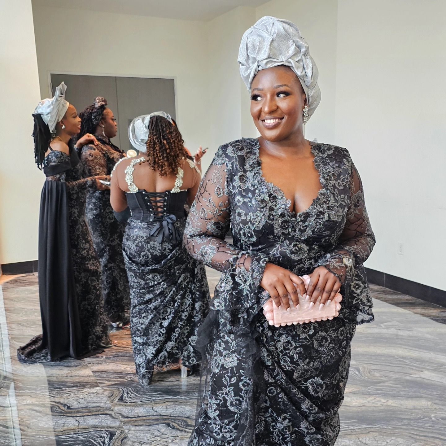 A woman in a black dress is standing in a room with other women