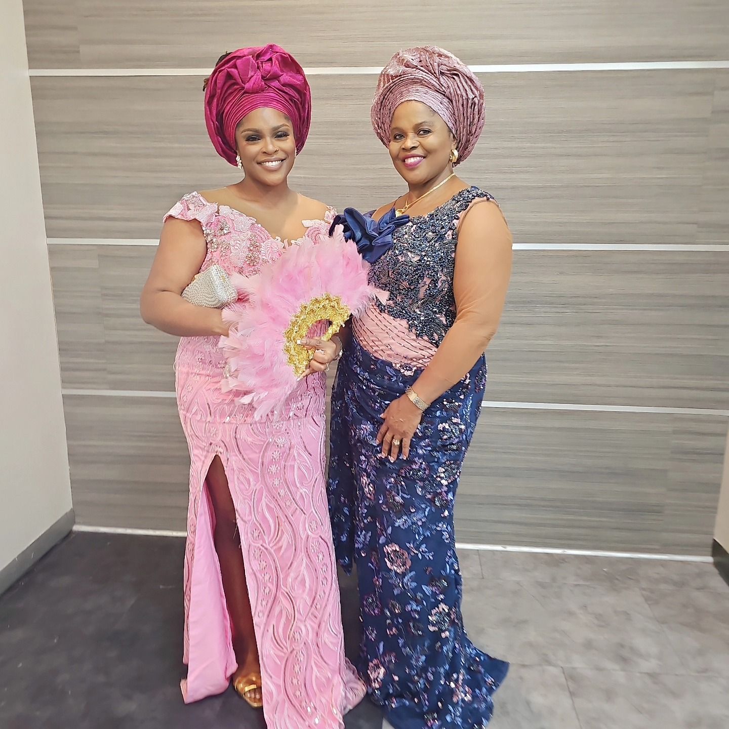 Two women standing next to each other one in a pink dress and one in a blue dress