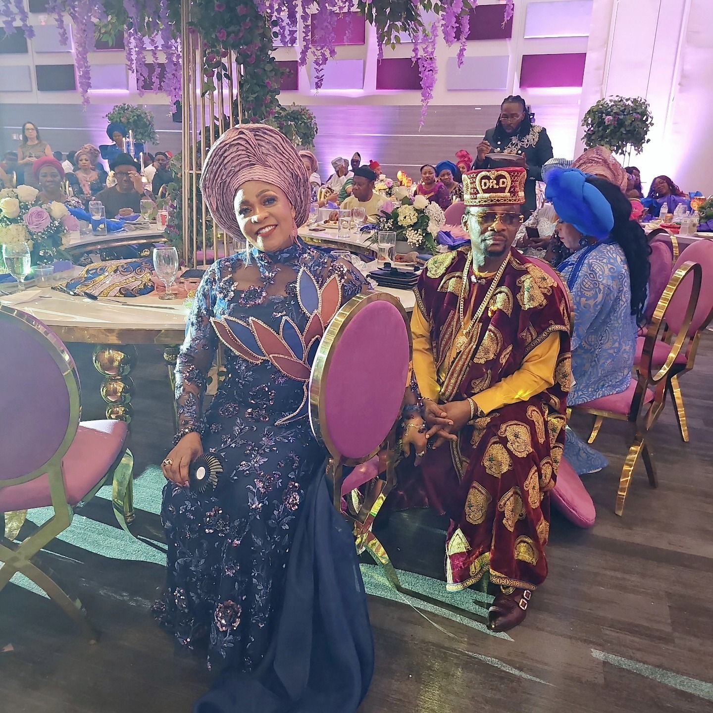 A group of people are sitting at tables and chairs at a wedding reception.