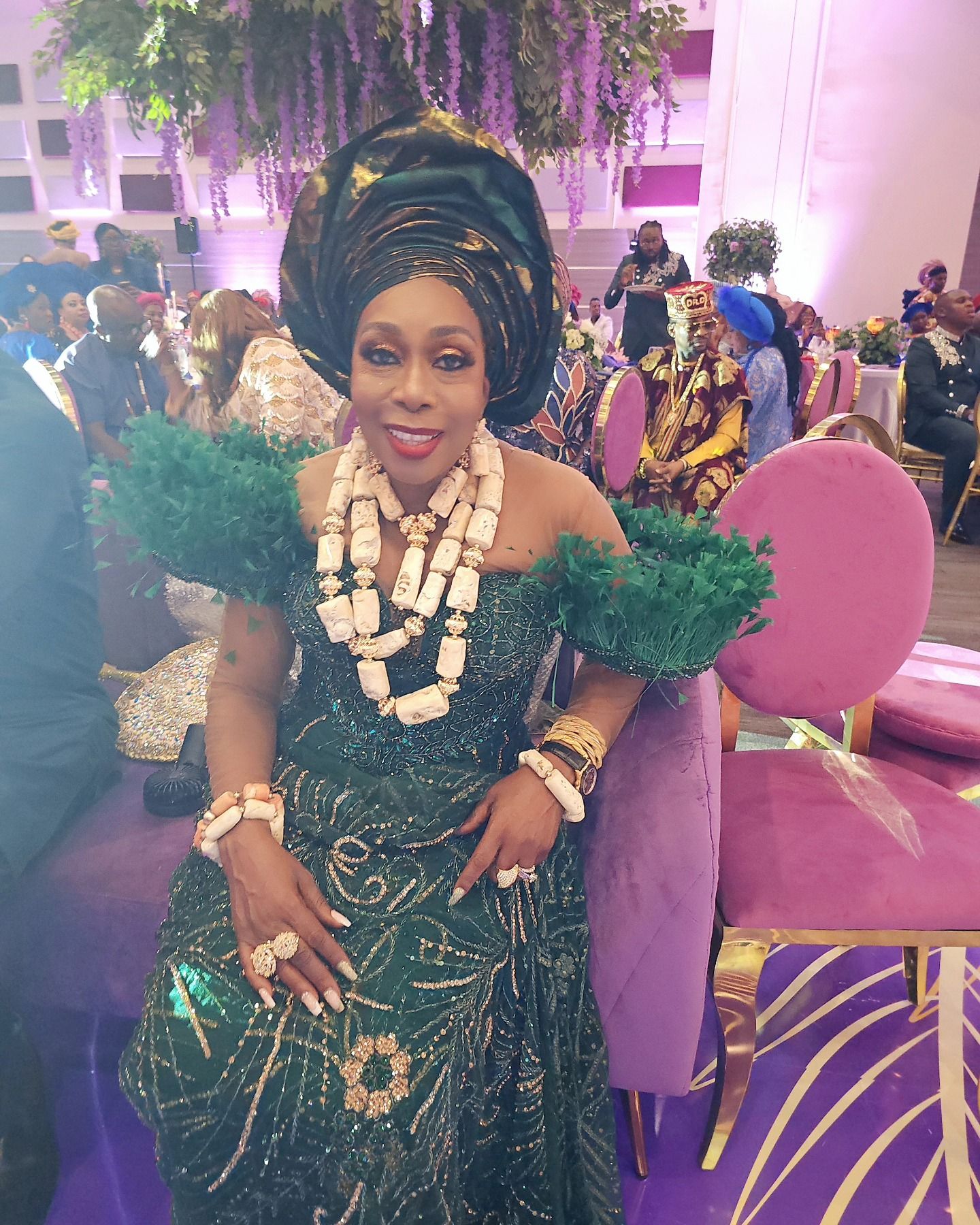 A woman in a green dress is sitting in a chair.