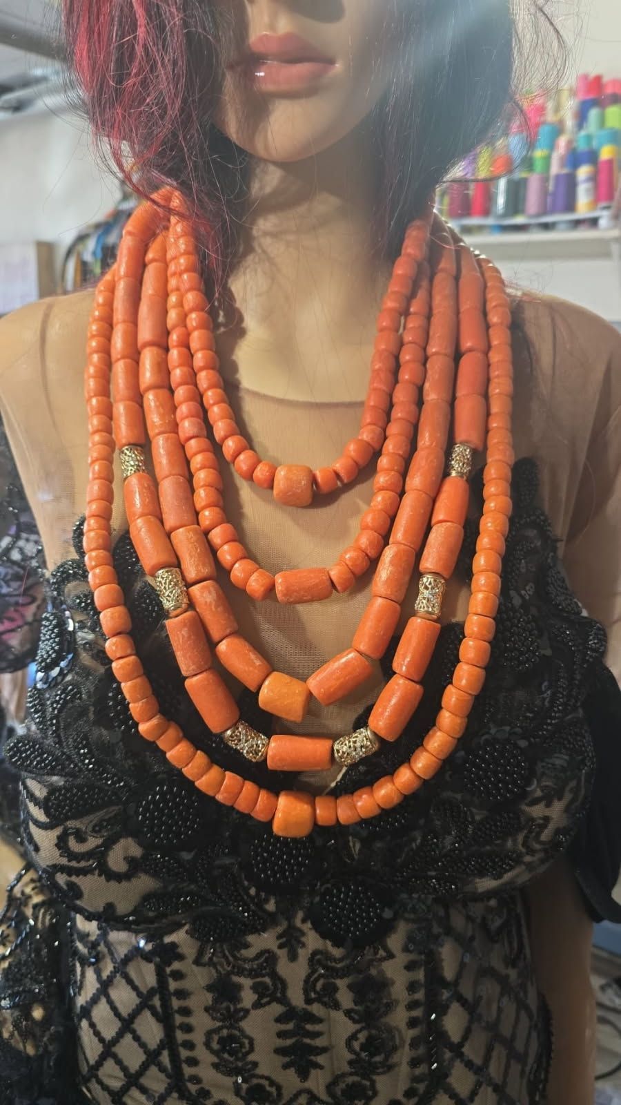 A woman is wearing a necklace made of orange beads.