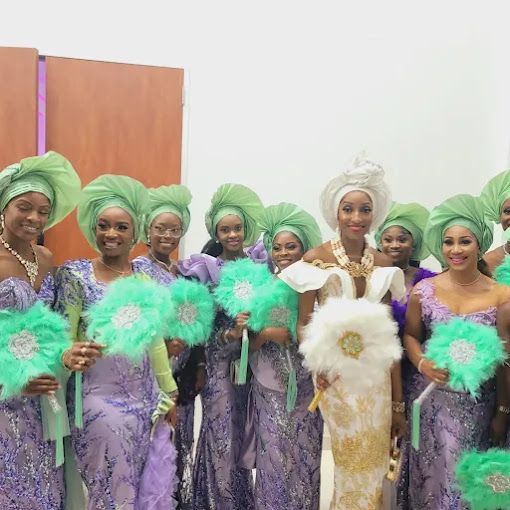 A group of women in purple dresses and green turbans are posing for a picture.